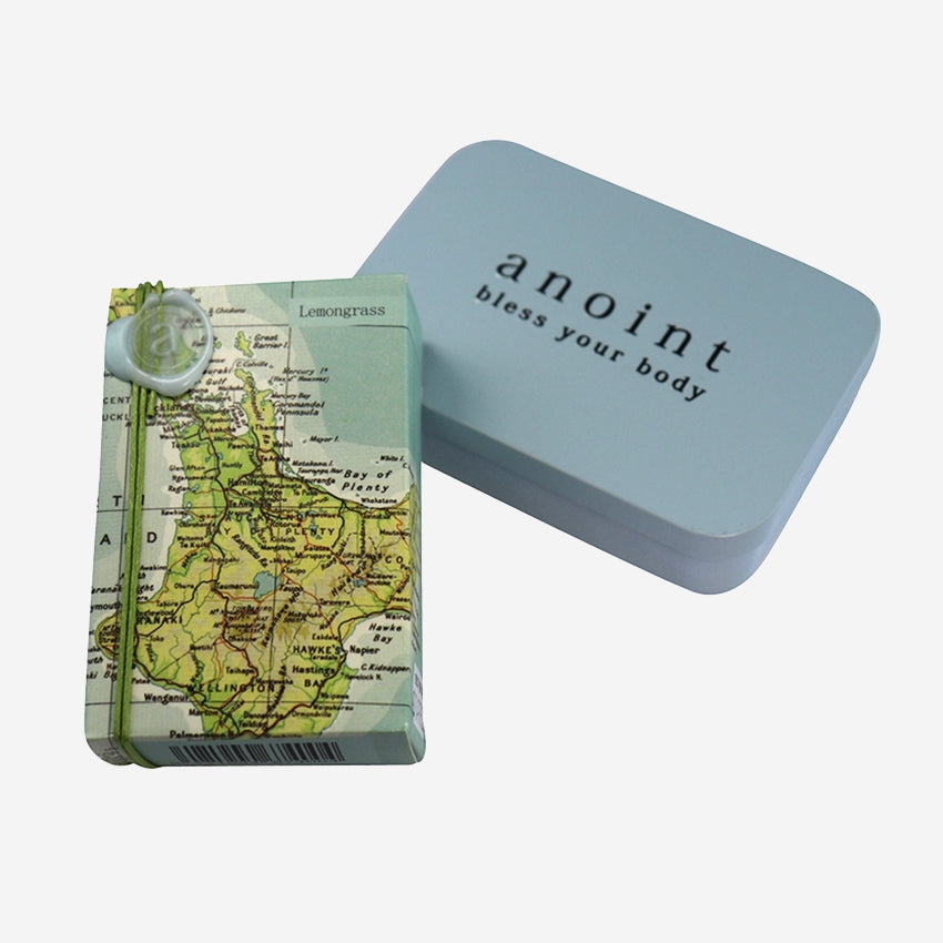The Anoint Lemongrass Lotion Bar next to the tin on a blank background