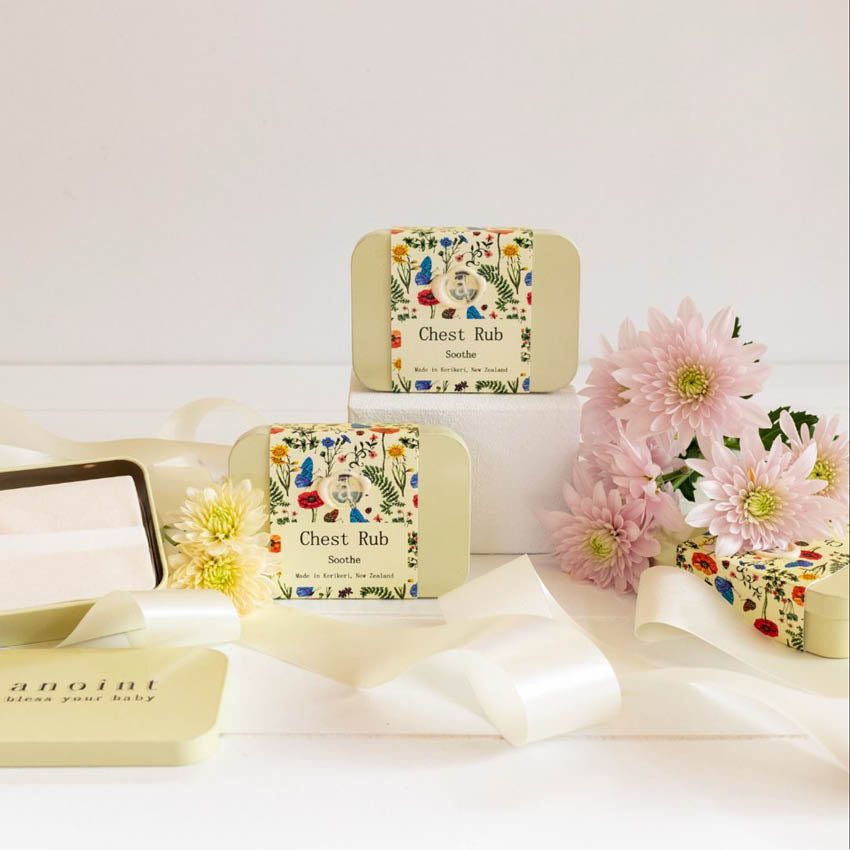The Anoint Chest Rub tins on a styled setting with flowers and ribbons