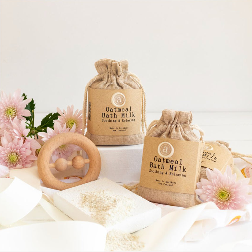 Two of the Anoint Oatmeal Bath Milks in a styled shot with flowers