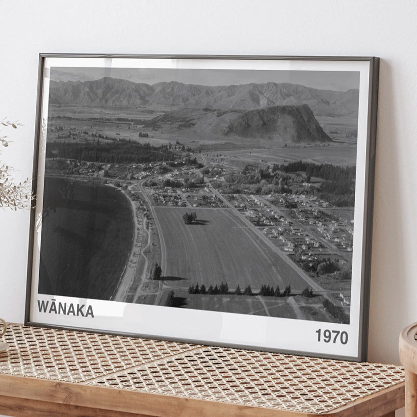 The ARTORY Wanaka 1970 looking towards Mt Iron Art Print in a black frame on a bench