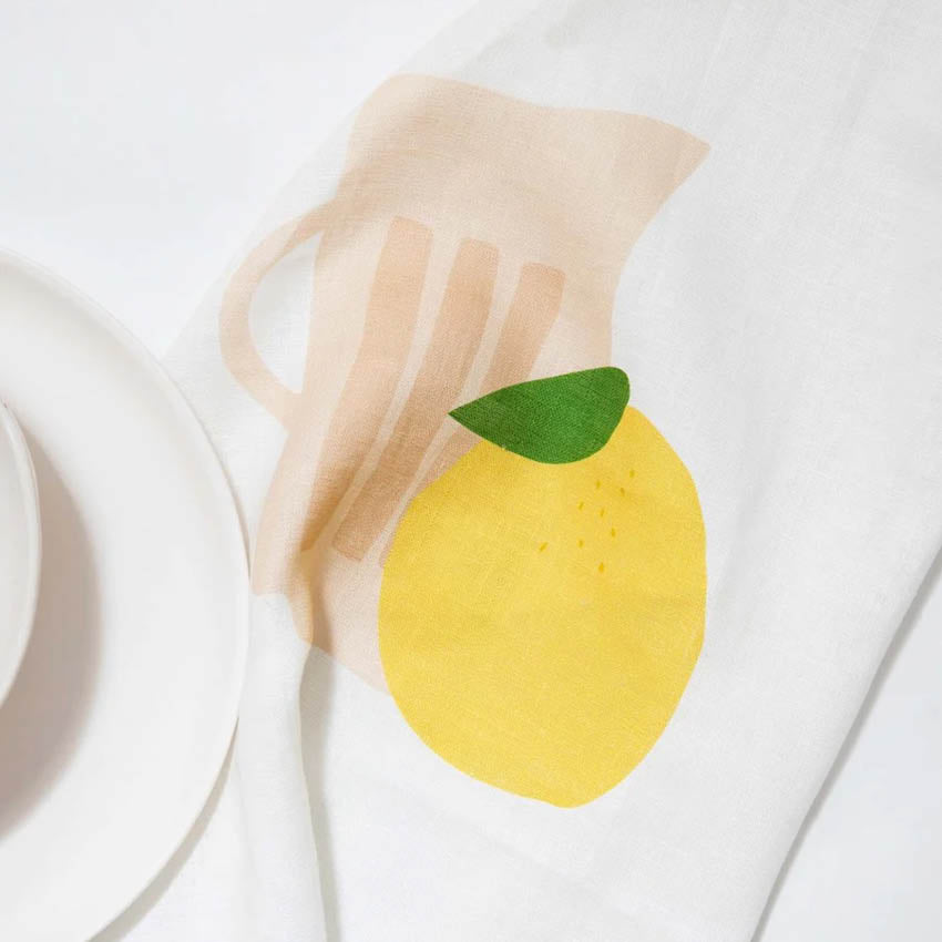 The Father Rabbit Tea Towel in the Jug with Lemon design with a plate on it