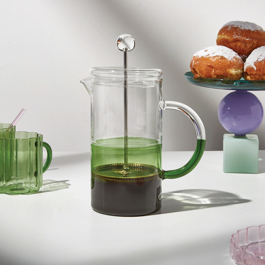 The Fazeek Two Tone Coffee Plunger in Clear and Green on a table with the fazeek wave mugs, cake stand and more.