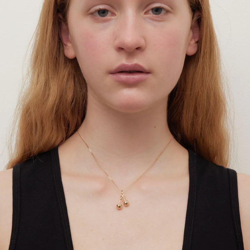 The Meadowlark Cherry Charm Necklace in gold on a model