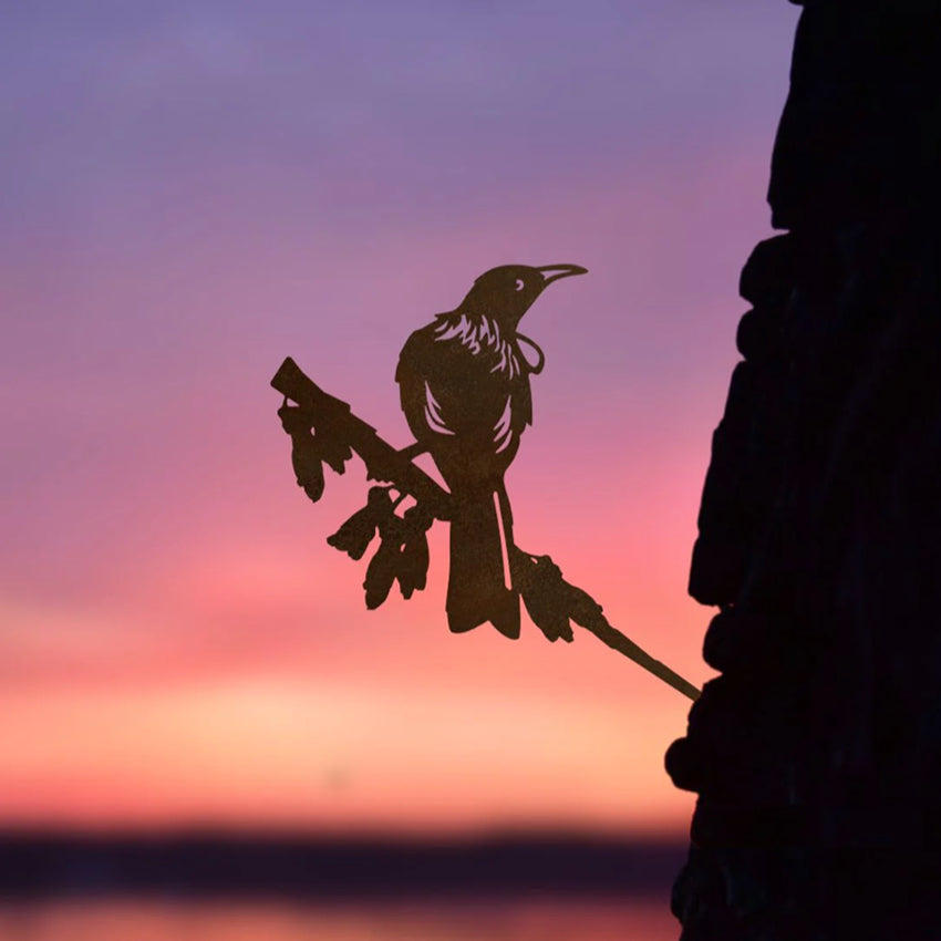 The Metalbird Centennial Tui in a tree with a sunset in the background