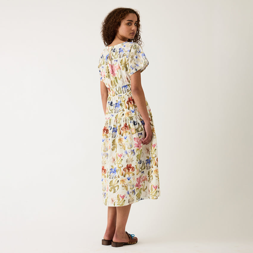 A back view of the Nancybird Lola Dress in Watercolour Collage on a model on a grey background