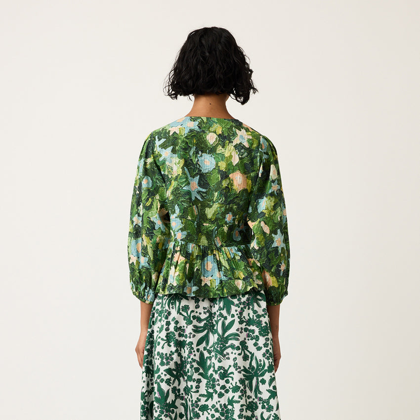 A back view of the Nancybird Mabel Top in Garden on a model on a grey background