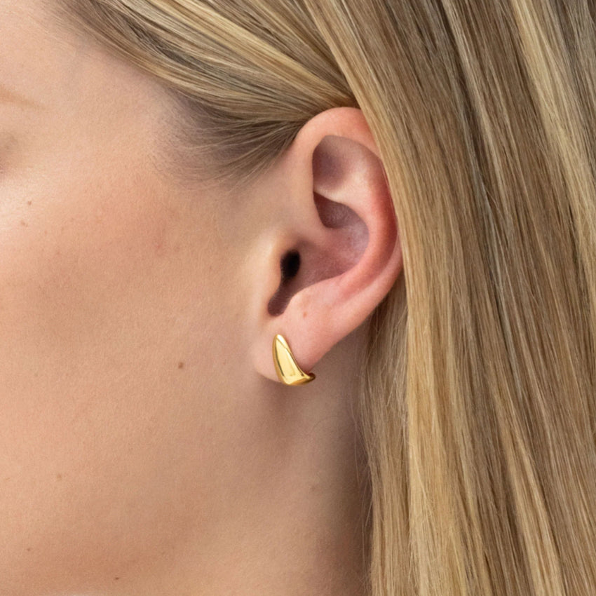 The Nina Gordon Rosco Earrings in Gold on a model