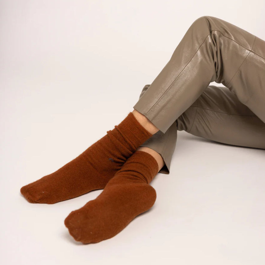 Brown Nooan Hamilton Possum and Merino Wool socks worn with beige pants on a white background