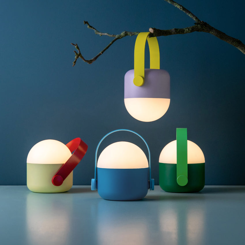 Four of the Remember Light Ole lamps on a dark blue background with one hanging from a branch