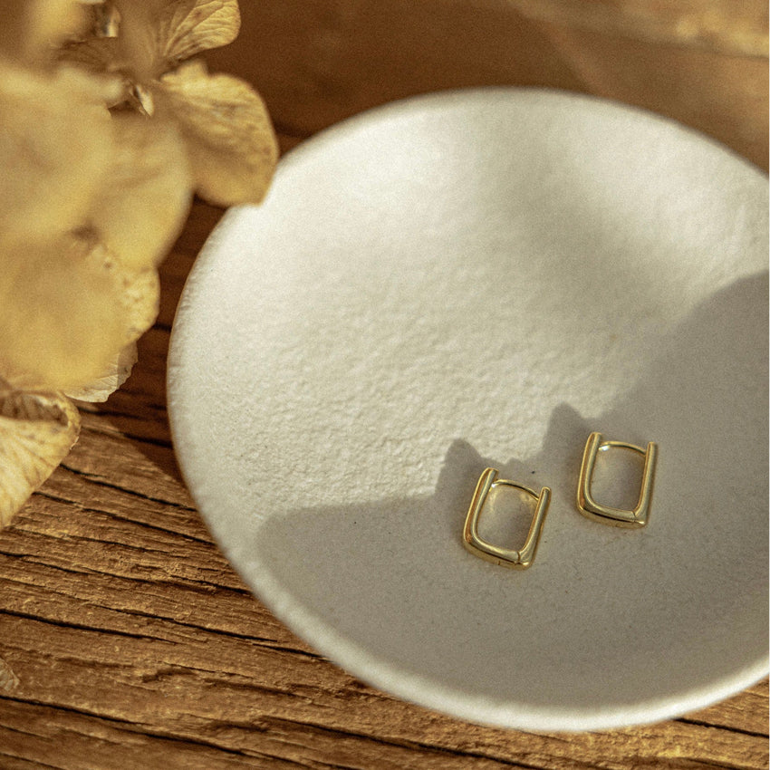 The Silver Linings Collective Marle Earrings in Gold on a trinket bowl
