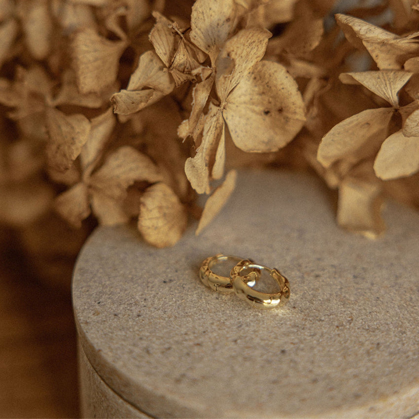 The Silver Linings Collective Scarlet Hoops in Gold on a textured trinket box
