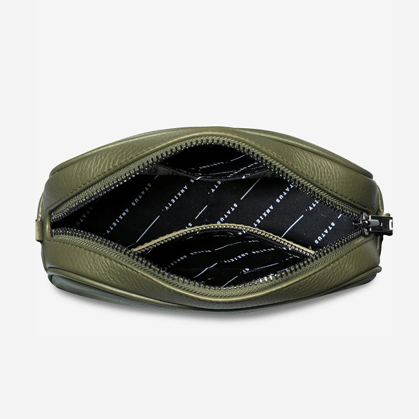 Top view of an open Status Anxiety Plunder Bag with a Webbed Strap in Khaki on a blank background