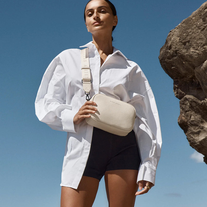 The Status Anxiety Plunder Bag with Webbed Strap in Chalk on a model