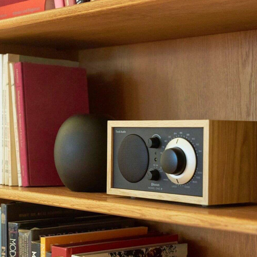 The Tivoli Audio Model One BT in Oak and Black on a book shelf