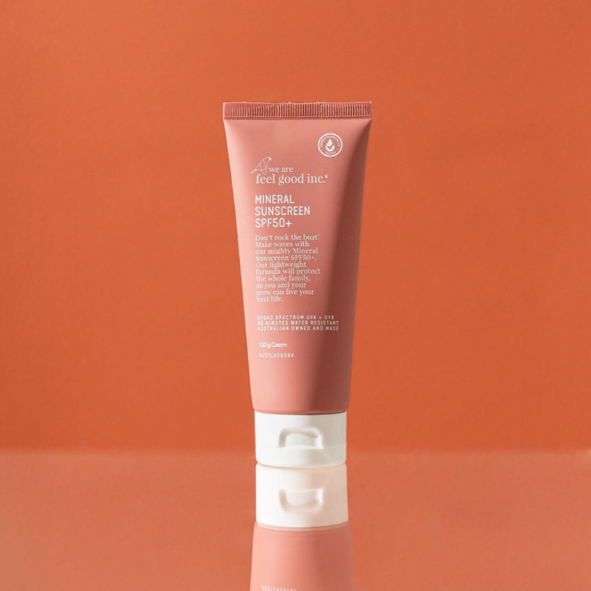 The We Are Feel Good Inc Mineral Sunscreen SPF 50+ 100g Tube on a orange background