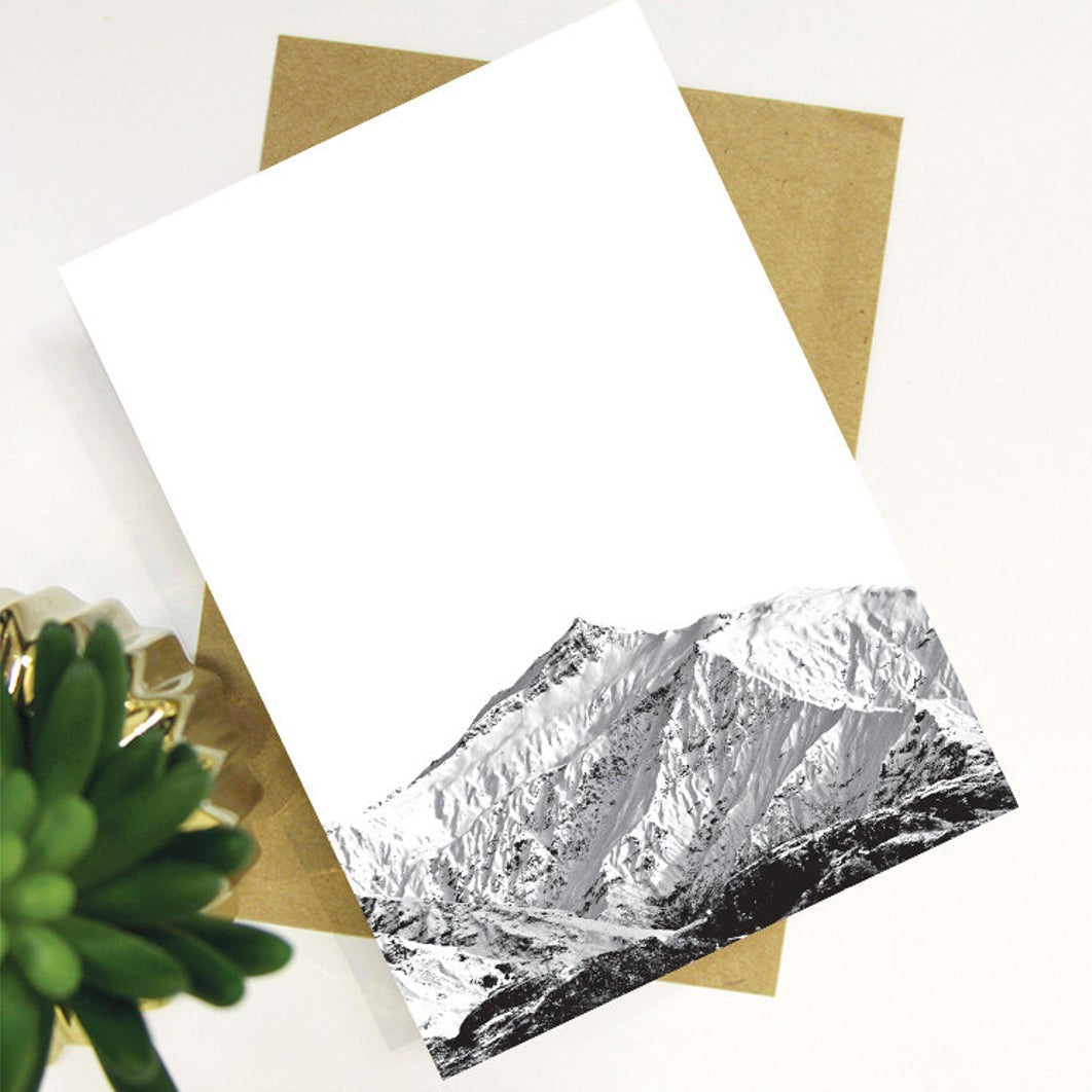 The Bridget Hall Black Peak Image Gift Card on top of an envelope next to a plant