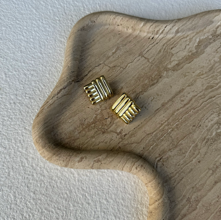 The Silver Linings Collective Di Earrings in Gold on a textured tray