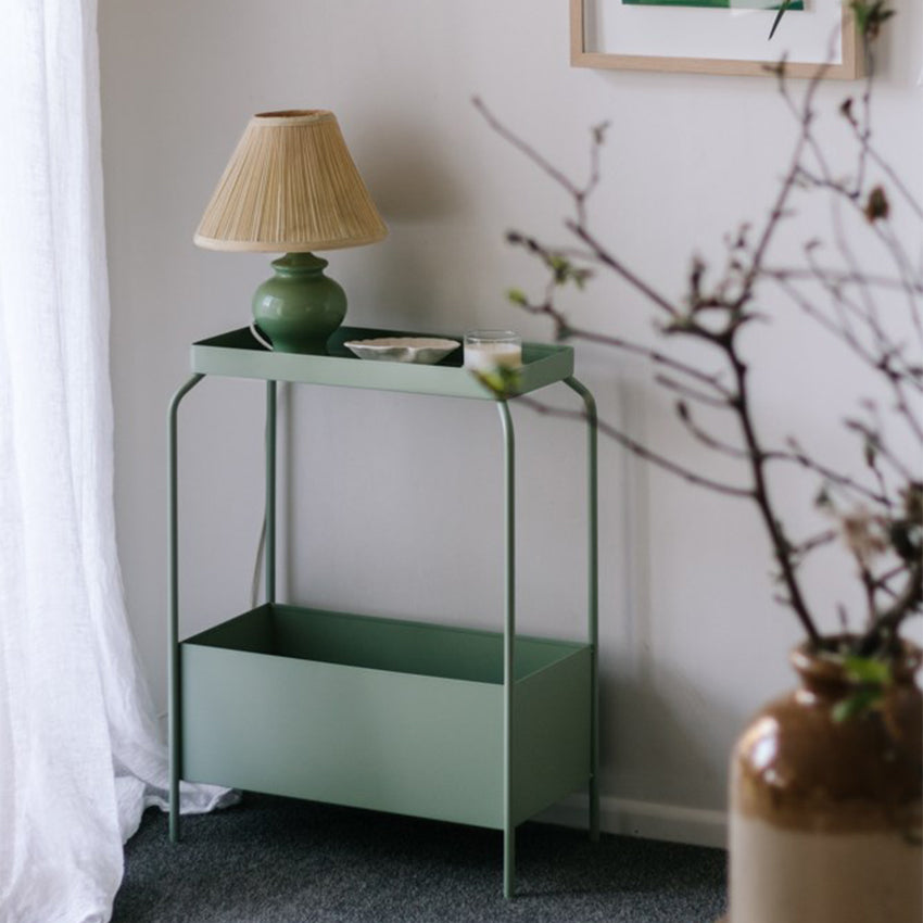Garcia Metal Planter Stand in Sage Green in living room with lamp, dish and candle on it.