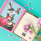 The 100 Percent NZ Jigsaw Puzzle with artwork of birds and a teacup by Angie Dennis open on a bench