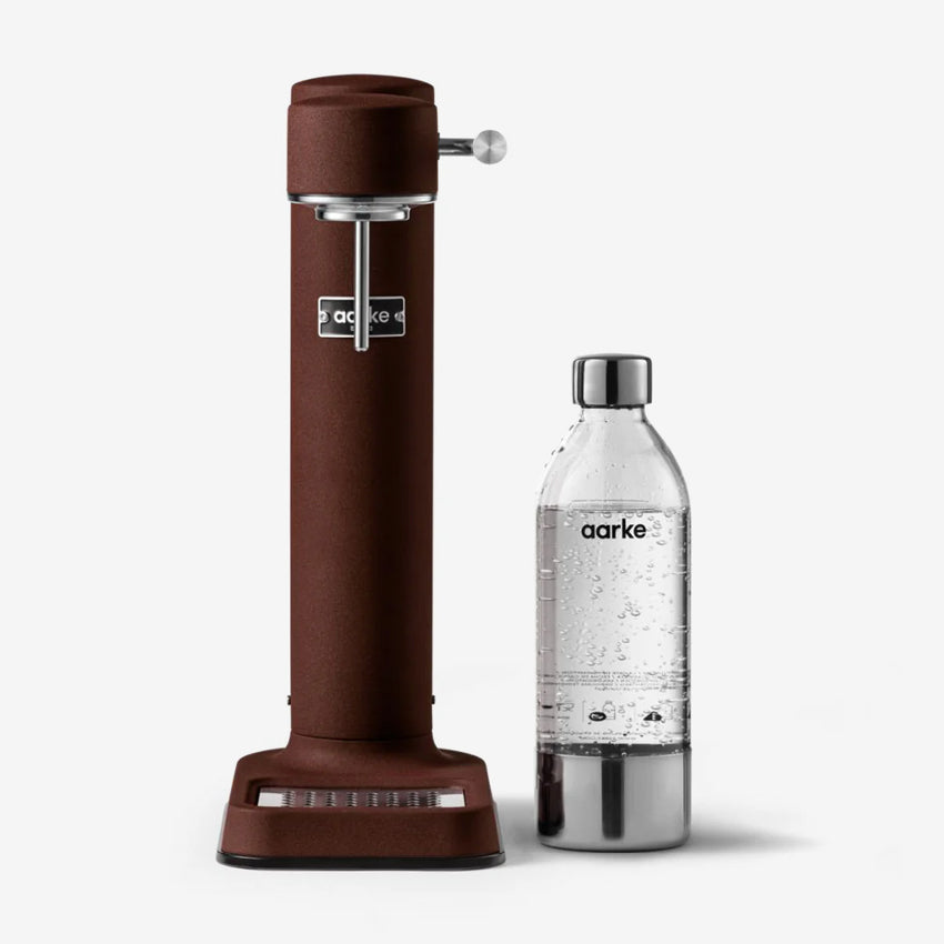 The Aarke Carbonator 3 in Burgundy next to the bottle