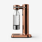 The side profile of the Aarke Carbonator 3 in Copper with the PET water bottle on a blank background