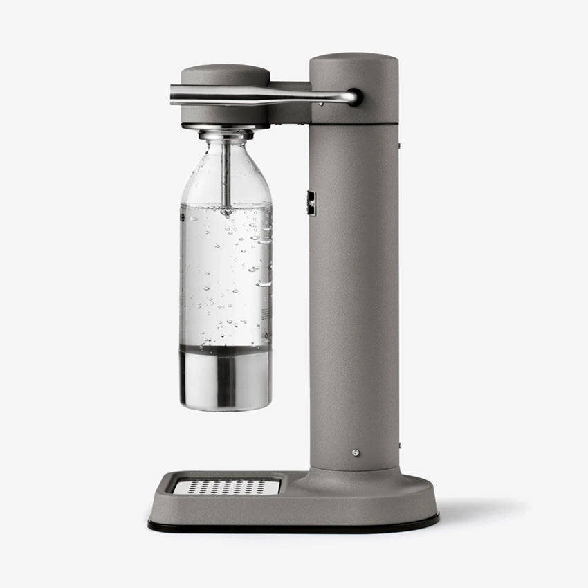 The Aarke Carbonator 3 in Matte Grey with a PET water bottle on a blank background