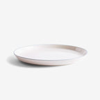 An Acme Roman Small Plate in Milk with Kokako 002 on a grey background