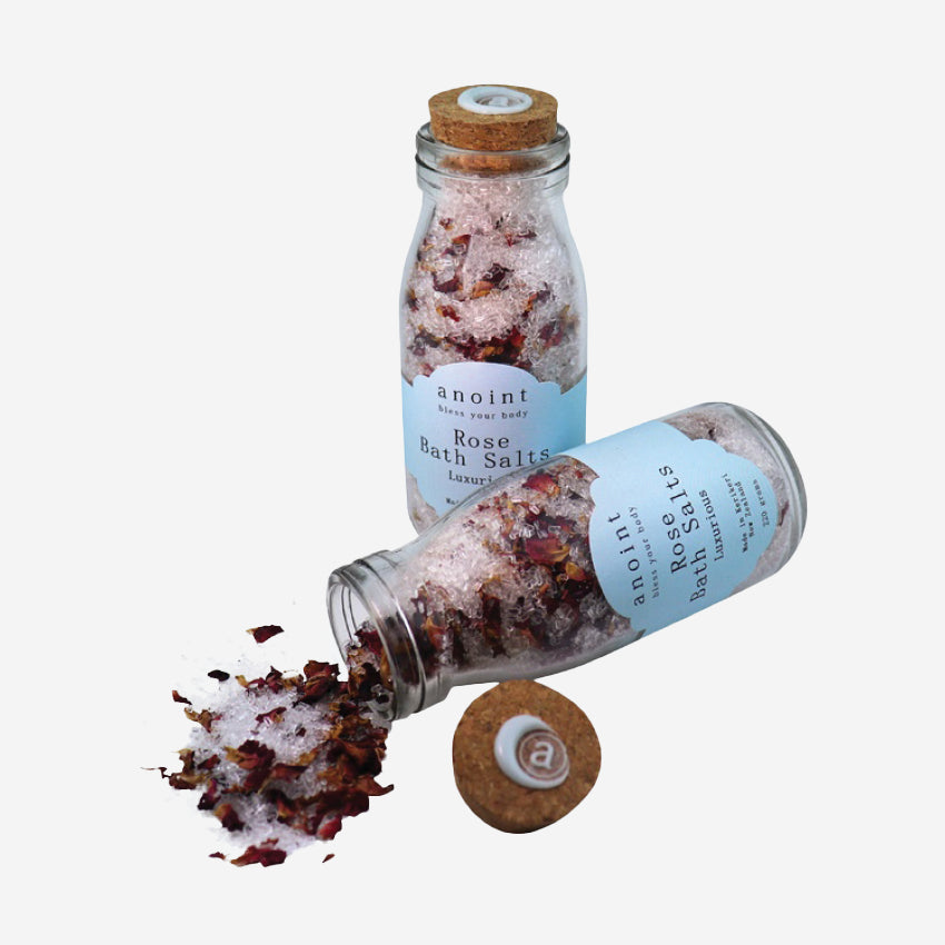 Two of the Anoint Rose Bath Salts jars with one spilling out on a blank background