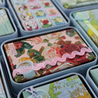 The Anoint Ylang Ylang Lotion bar in its tin next to other anoint lotion bars
