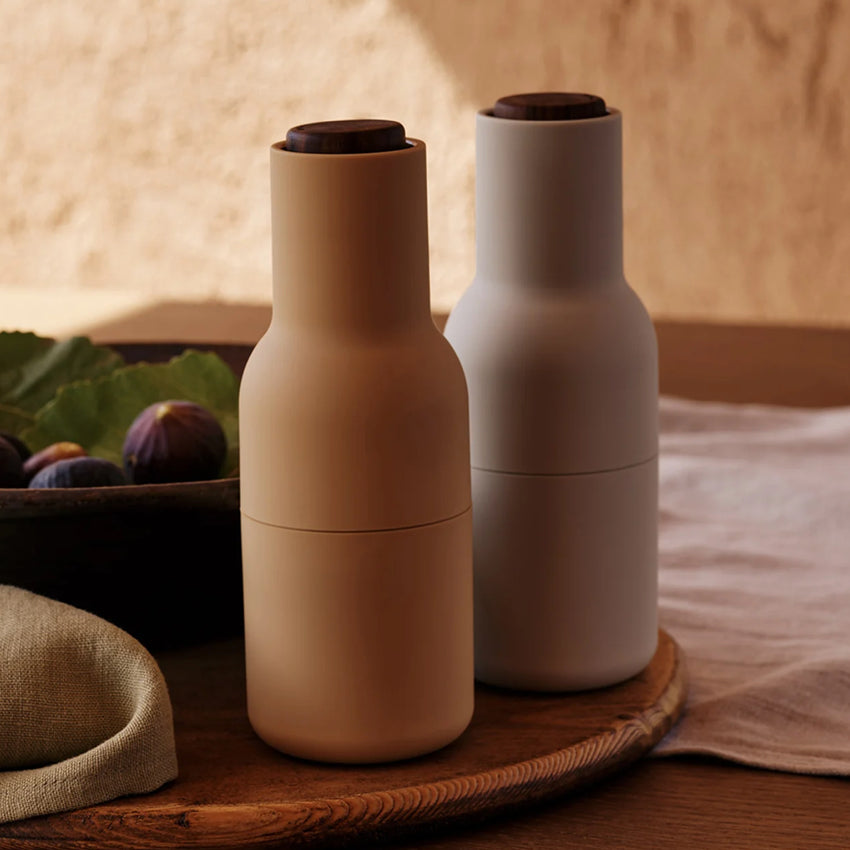 The Audo previously known as Menu Salt and Pepper Bottle Grinders in Barley with Walnut Lids on a wood tray