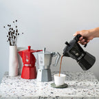The Bialetti Moka Exclusive Coffee Pot 6 cup size in Black with coffee being poured into a cup