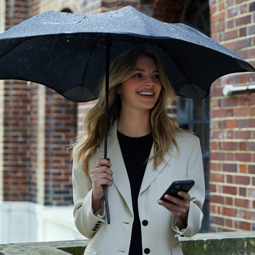 The Blunt Metro Umbrella in Navy with a model holding it