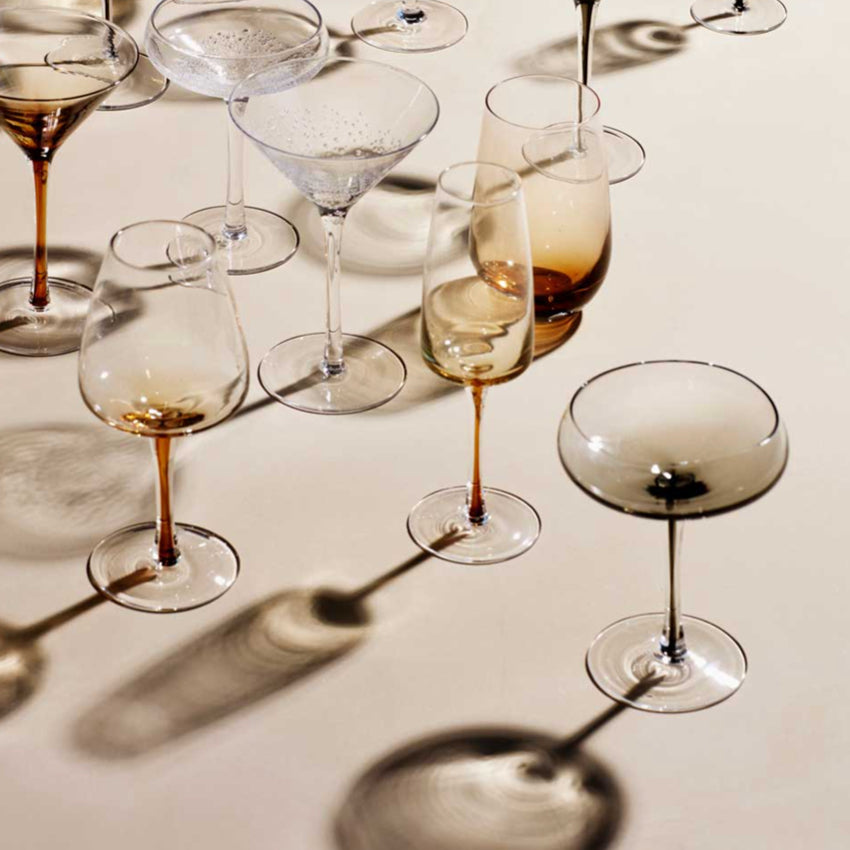 The Broste Copenhagen Champagne Glass in Amber with other Broste glassware surrounding it 