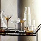 The Broste Copenhagen Cocktail Glass in Amber on a bar cart with other Broste glassware