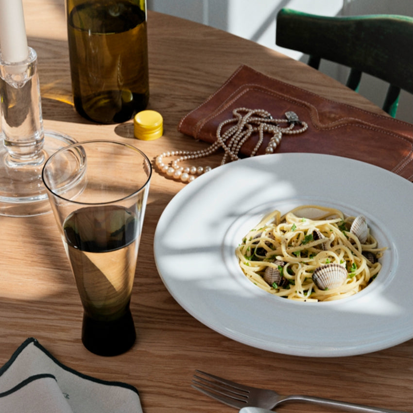 Broste Copenhagen Konus Short Cocktail Glass in Green on a table with a bowl of pasta