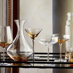 The Broste Copenhagen Martini Glass in Amber on a bar cart with other Broste glassware