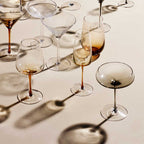 The Broste Copenhagen White Wine Glass in Amber surronded by other Broste glassware