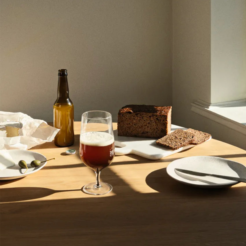 The Broste Coppenhagen Beer Glass in Smoke on a table with bread, cheese and more.