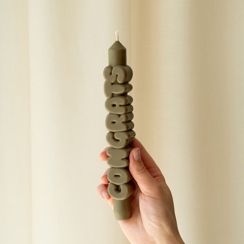A hand holding the Candle Hand Congrats 3D Taper Candle in olive