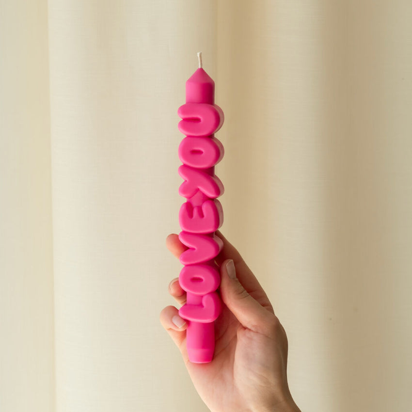 A hand holding the CandleHand Love You 3D Taper Candle in pink
