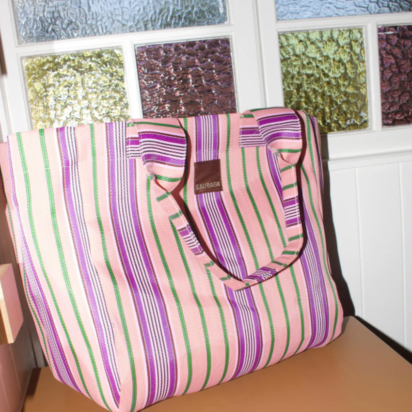 The EAU Grand Bag in Wild Clay in front of stained glass 