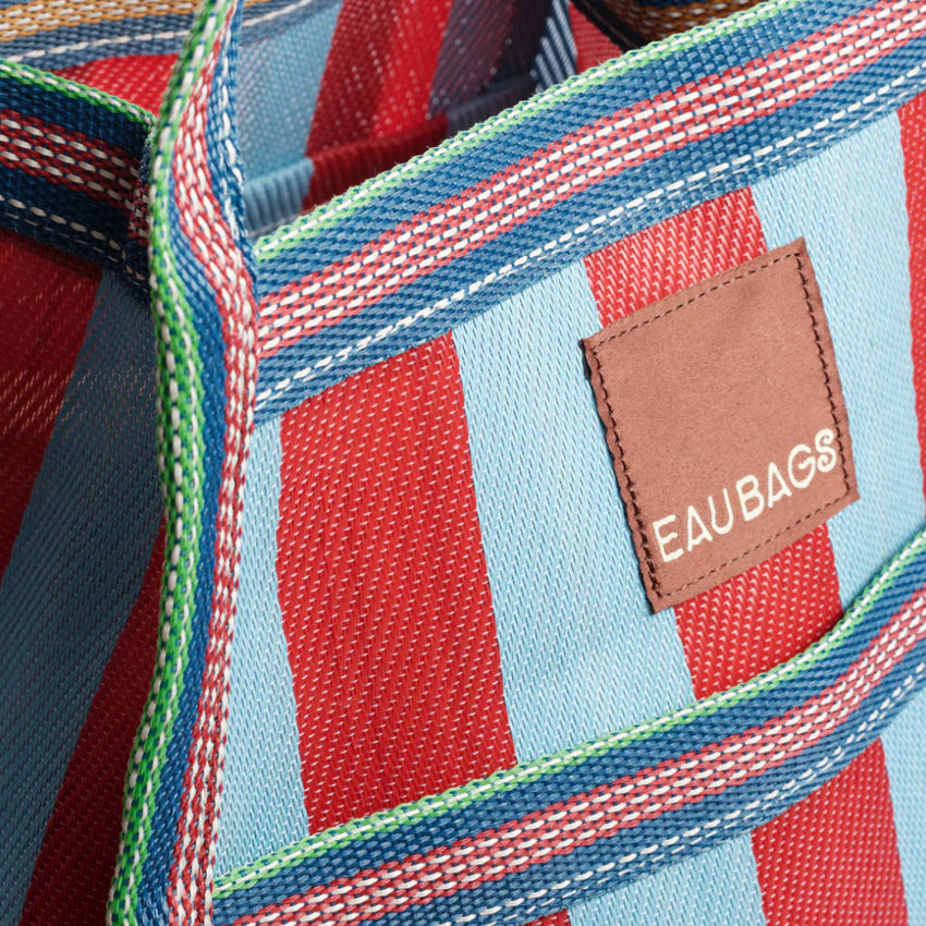 A close up of the EAU Sac Bag in Club Rouge on a grey background