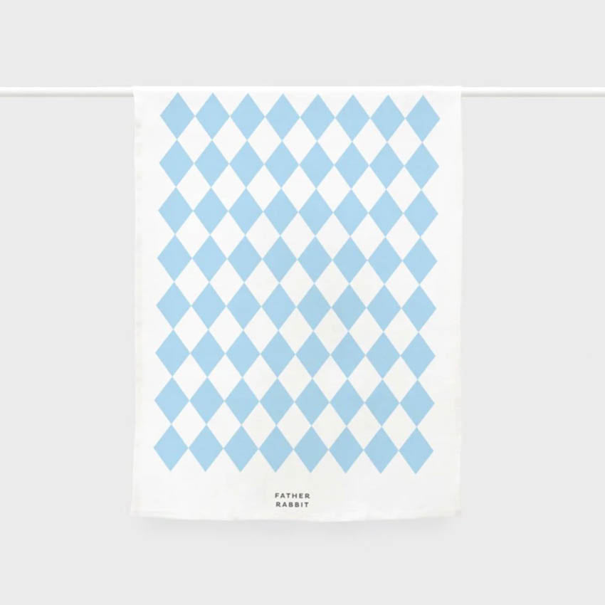 The Father Rabbit Tea Towel in Blue Diamonds hanging on a rod on a blank background