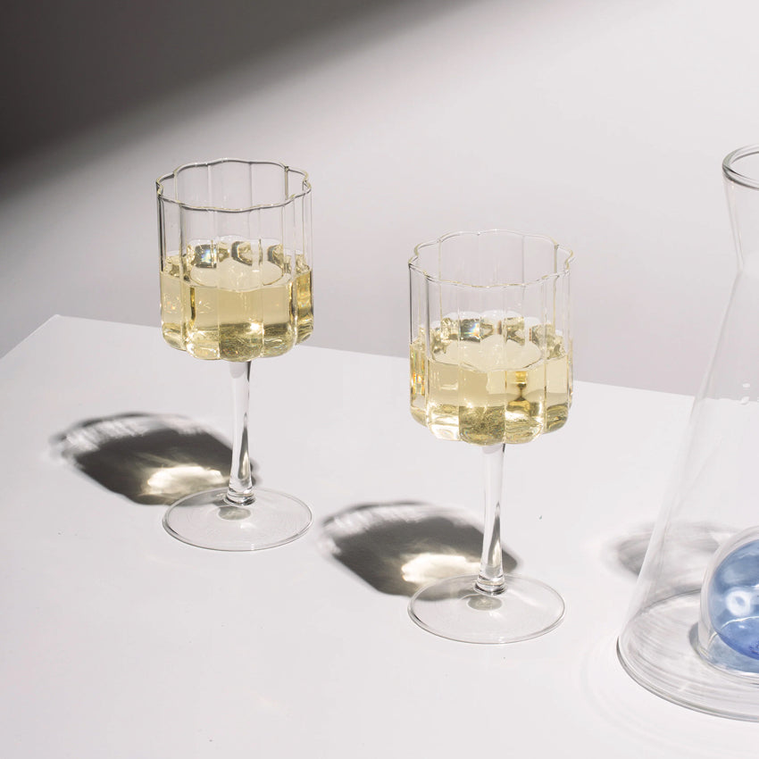 The Fazeek Wave Wine Glasses in Clear with white wine in them next to a fazeek decanter