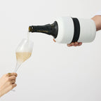 The Huski Champagne Cooler in White with a champagne bottle in it pouring into a champagne glass