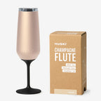 The Huski Champagne Flute in the Champagne colour next to its box on a blank background