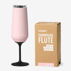 The Huski Champagne Flute in Powder Pink next to its box on a blank background
