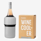 The Huski Wine Cooler in Stone Grey with a wine bottle in it and next to its box on a blank background