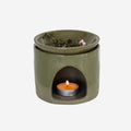 The JS Ceramics Ceramic Oil Burner in Sage Green with Manuka in it and candle in the bottom on a blank background