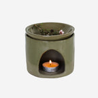The JS Ceramics Ceramic Oil Burner in Sage Green with Manuka in it and candle in the bottom on a blank background